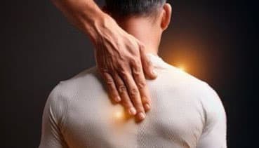 Eine Hand ruht auf dem Rücken einer Person, von dem Lichtstrahlen ausgehen, was Heilung und energetische Balance symbolisiert.